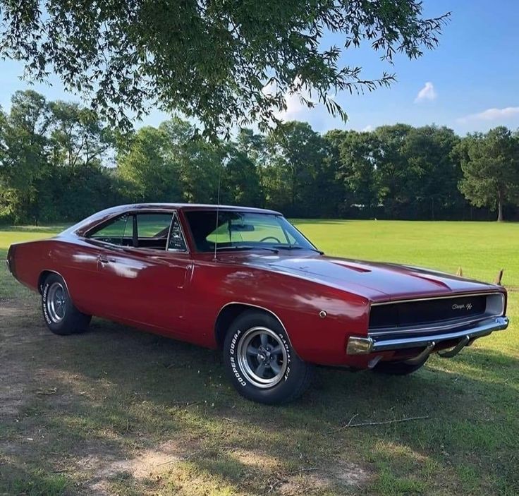 an old red car parked in the grass