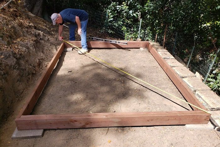 a man in blue shirt and jeans working on a wooden frame