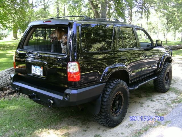 a large black suv parked on the side of a road with a dog in it