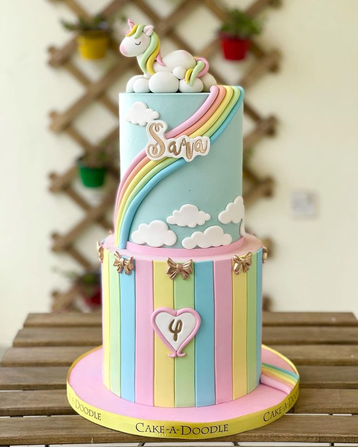 a multi layer cake decorated with rainbows and clouds