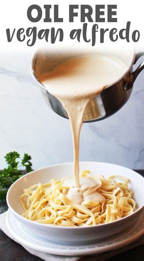 a white bowl filled with pasta and sauce being poured over it to make an oil free vegan alfredo