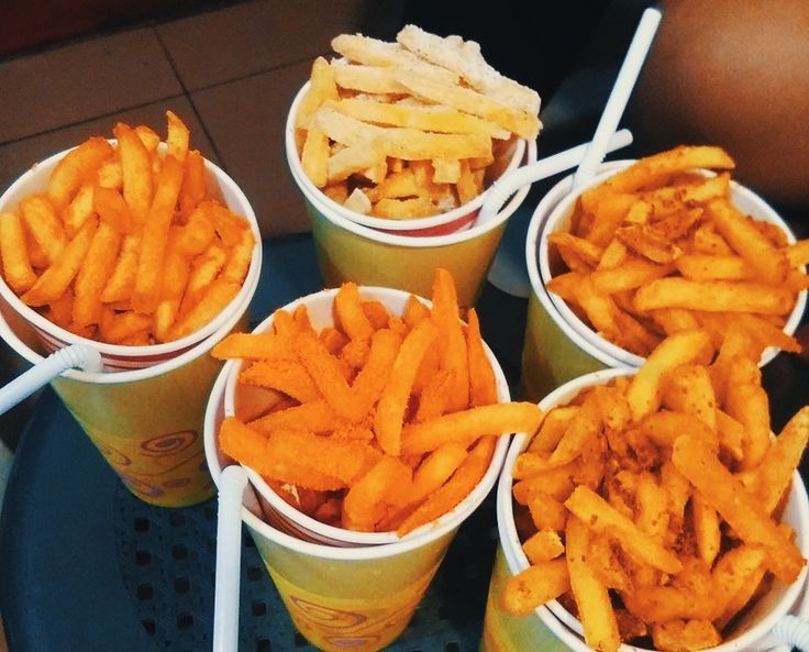 four cups filled with french fries sitting on top of a blue tray next to each other