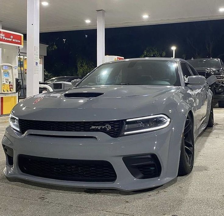 a grey dodge charger is parked at a gas station