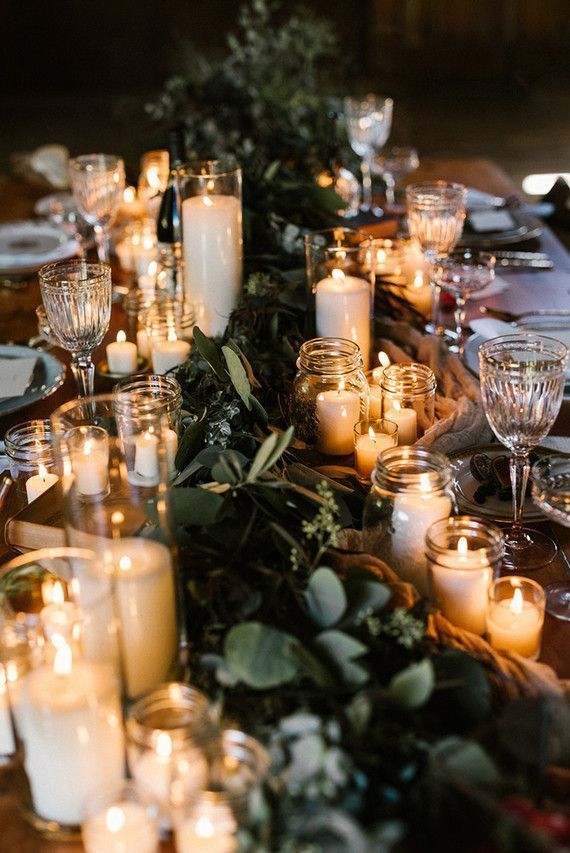 a table topped with lots of candles next to plates and glasses on top of a wooden table