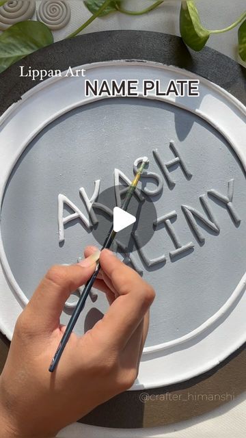 someone is drawing the name plate on a paper plate with scissors and paintbrushes