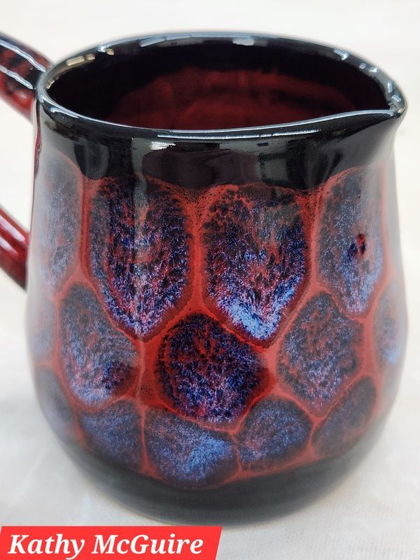 a red and black ceramic mug on a white table