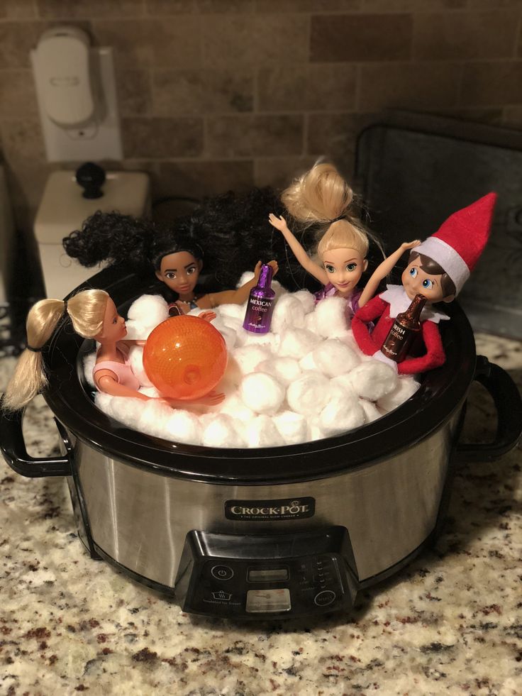 there are many dolls in the crock pot with cotton balls and other toys on top