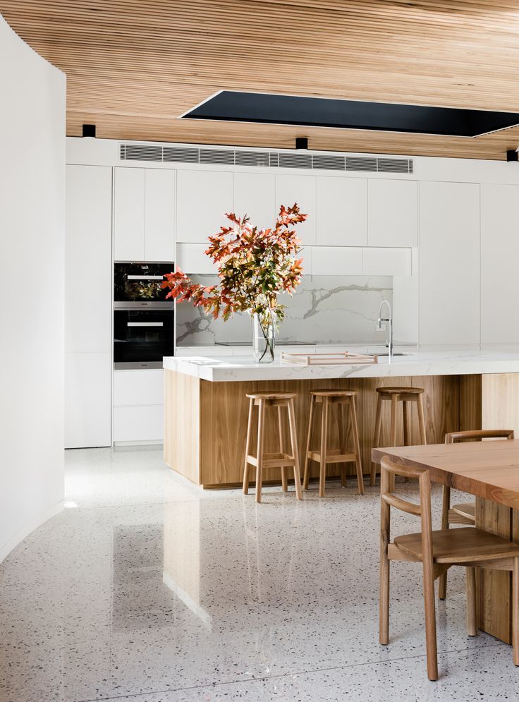 a kitchen with an island, table and stools next to it on the floor