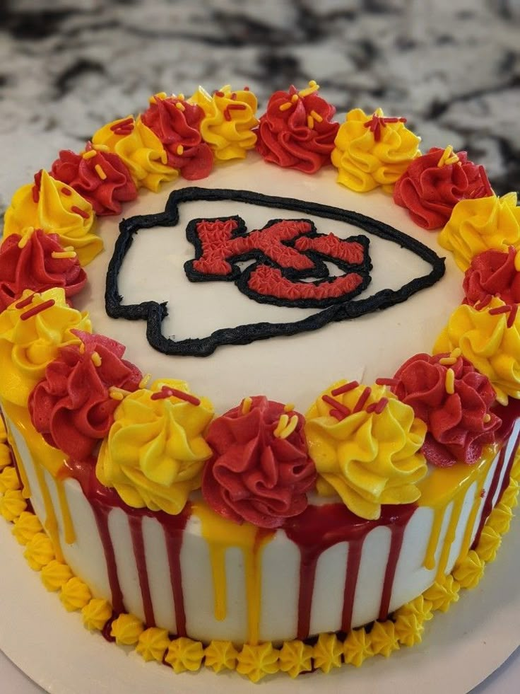 a cake decorated with flowers and a football logo on it's icing is sitting on a table