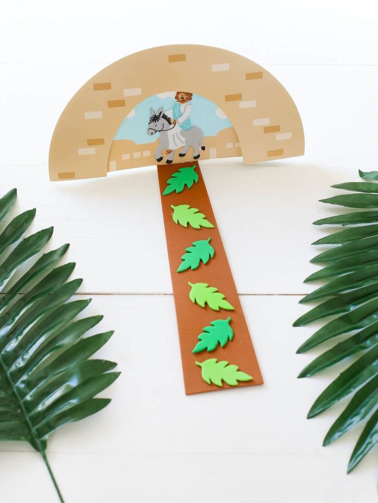 a paper cut out of a horse riding on a track with palm leaves around it