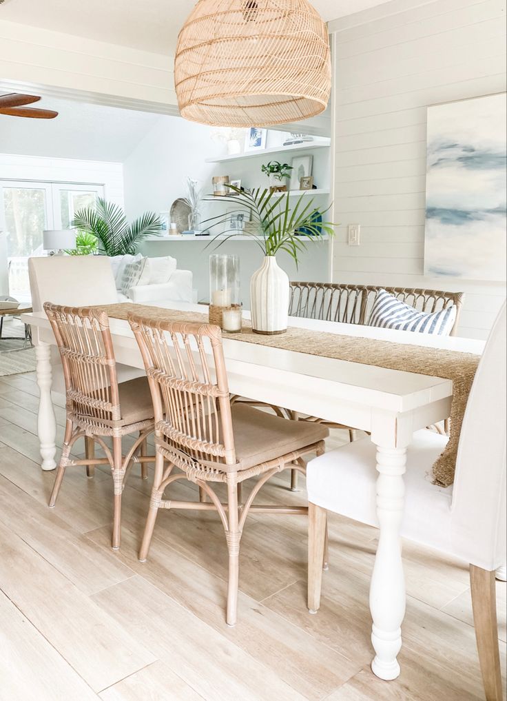 a white dining room table and chairs with wicker baskets hanging from the ceiling