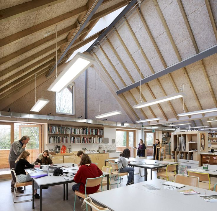 several people are sitting at tables in an open area with bookshelves and shelves