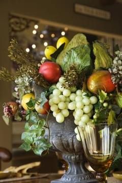 a vase filled with lots of different types of fruits and vegetables on top of a table