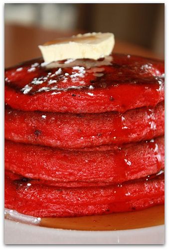 a stack of red pancakes with butter on top