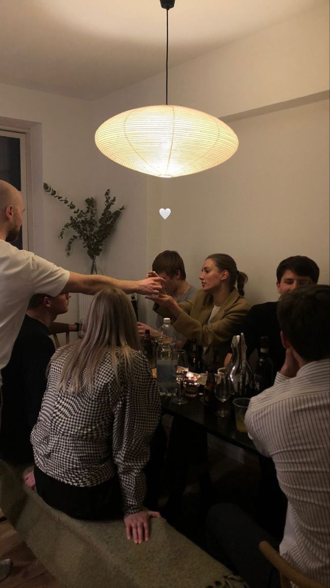 a group of people sitting around a table with wine glasses on it and one person reaching for something