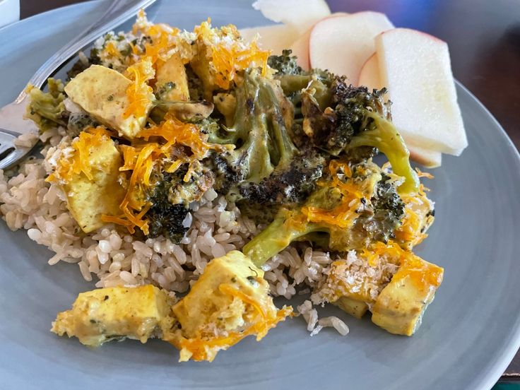 a white plate topped with rice and broccoli covered in cheese