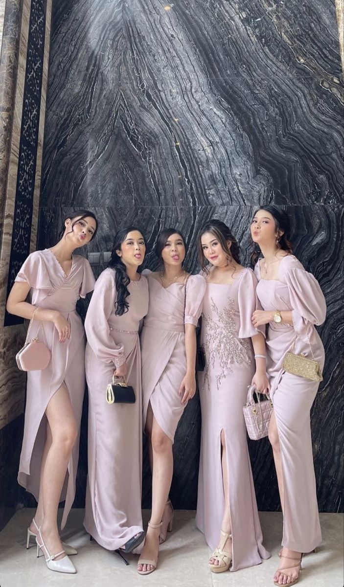 the bridesmaids are posing for a photo in front of a black marble wall