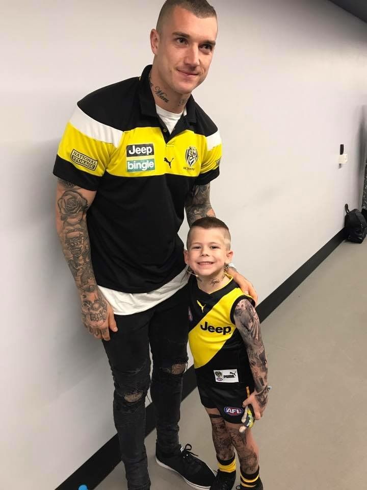 a man standing next to a little boy in a yellow and black shirt on top of a skateboard