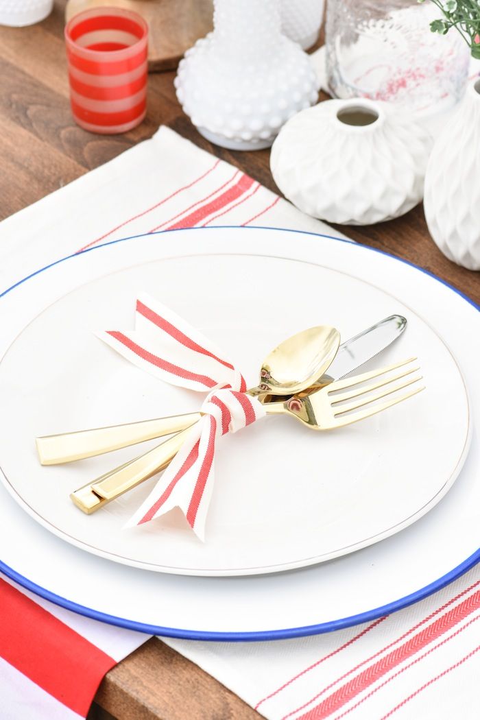 a white plate topped with two forks and a red and white striped napkin on top of a wooden table