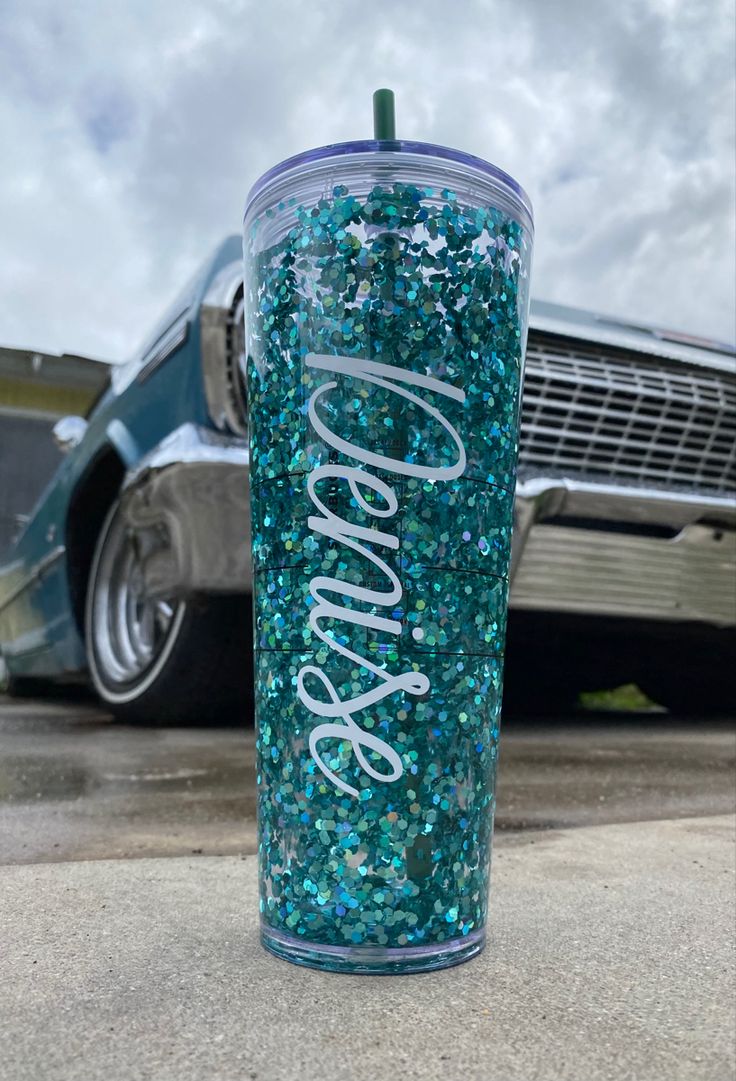 a blue glitter tumbler with the word sparkle on it sitting in front of a car