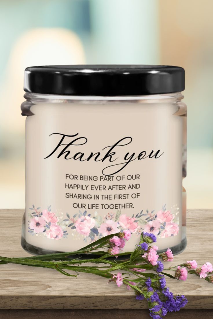 thank you jar with pink flowers and black lid sitting on a wooden table next to a purple flower