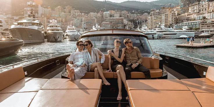 three people sitting on the back of a boat in front of a cityscape