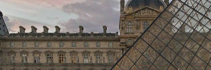 an old building with a glass pyramid next to it