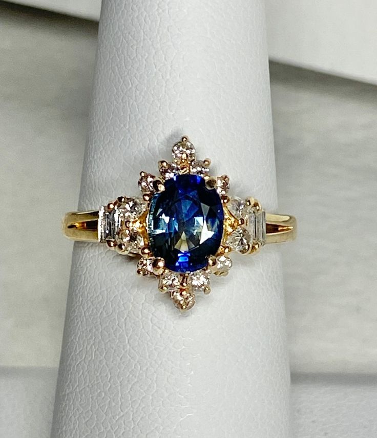 a blue and white diamond ring sitting on top of a white napkin with gold accents