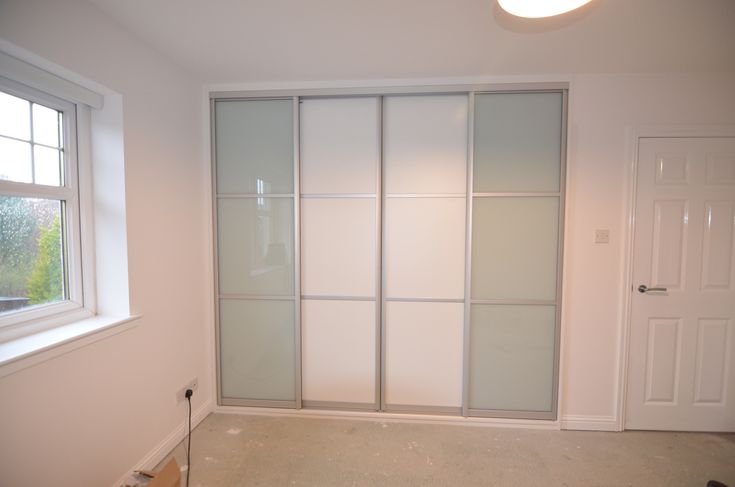 an empty room with sliding glass doors in the corner and a window on the far wall