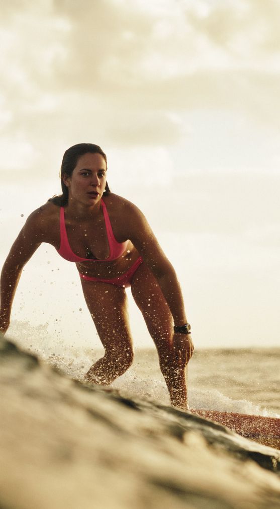 a woman riding a surfboard on top of a wave