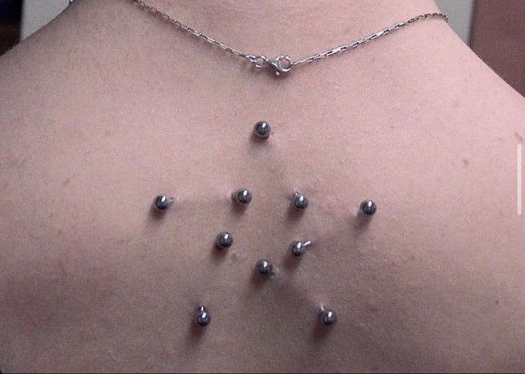 the back of a woman's neck with many balls attached to it and silver chains