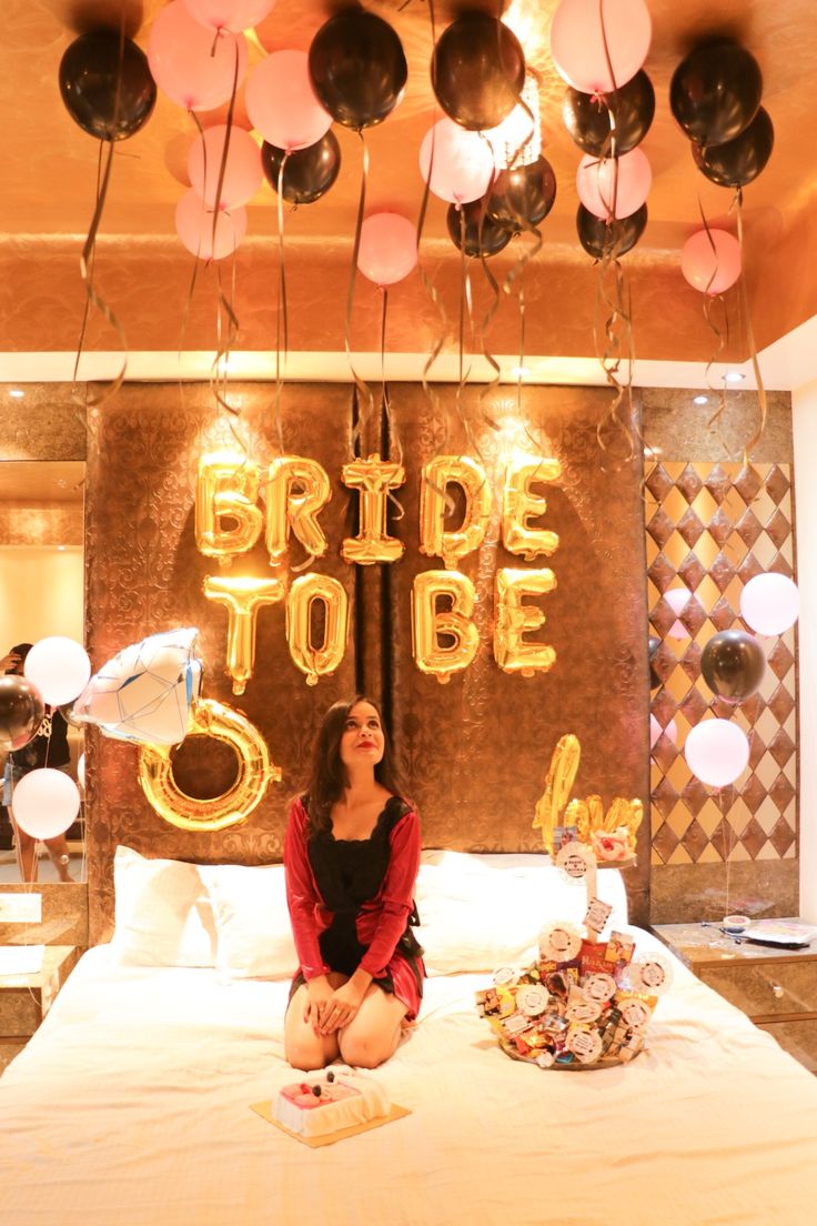 a woman sitting on top of a bed under balloons