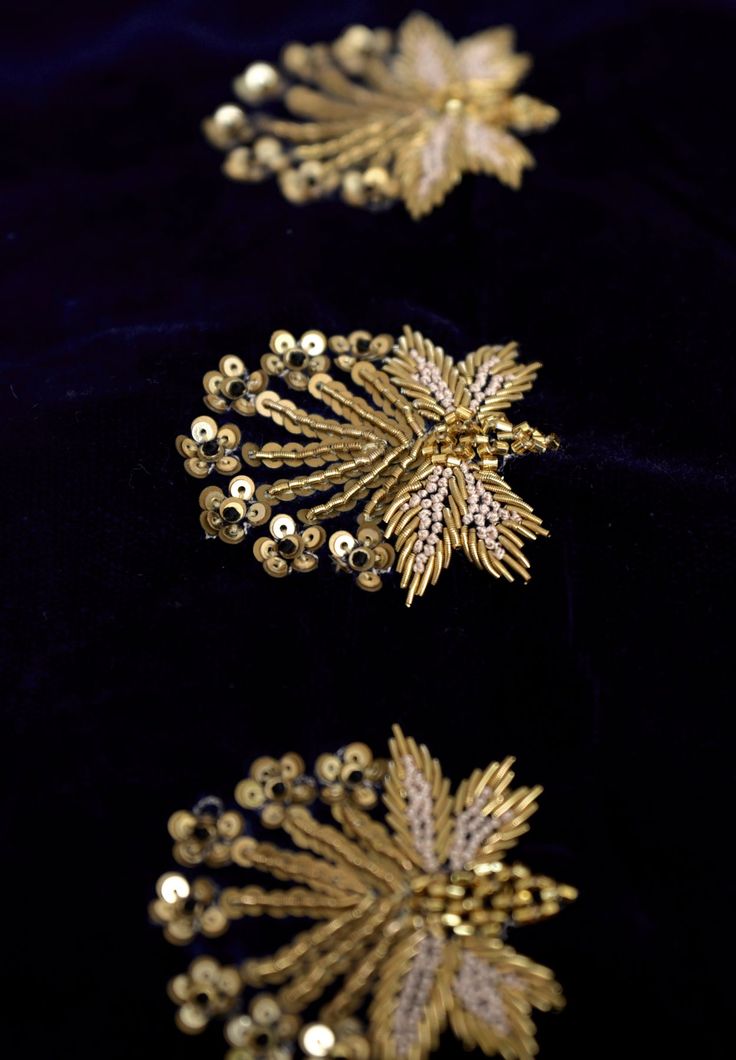 three gold brooches sitting on top of a black cloth