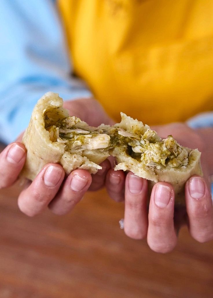 a person holding food in their hands on a wooden table