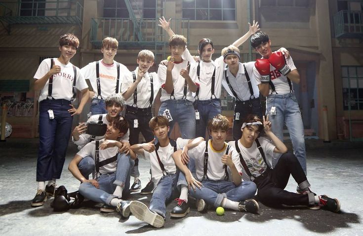 a group of young men posing for a photo in front of a building with their hands up