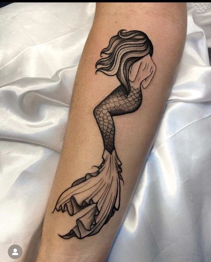 a black and white tattoo of a mermaid on the arm