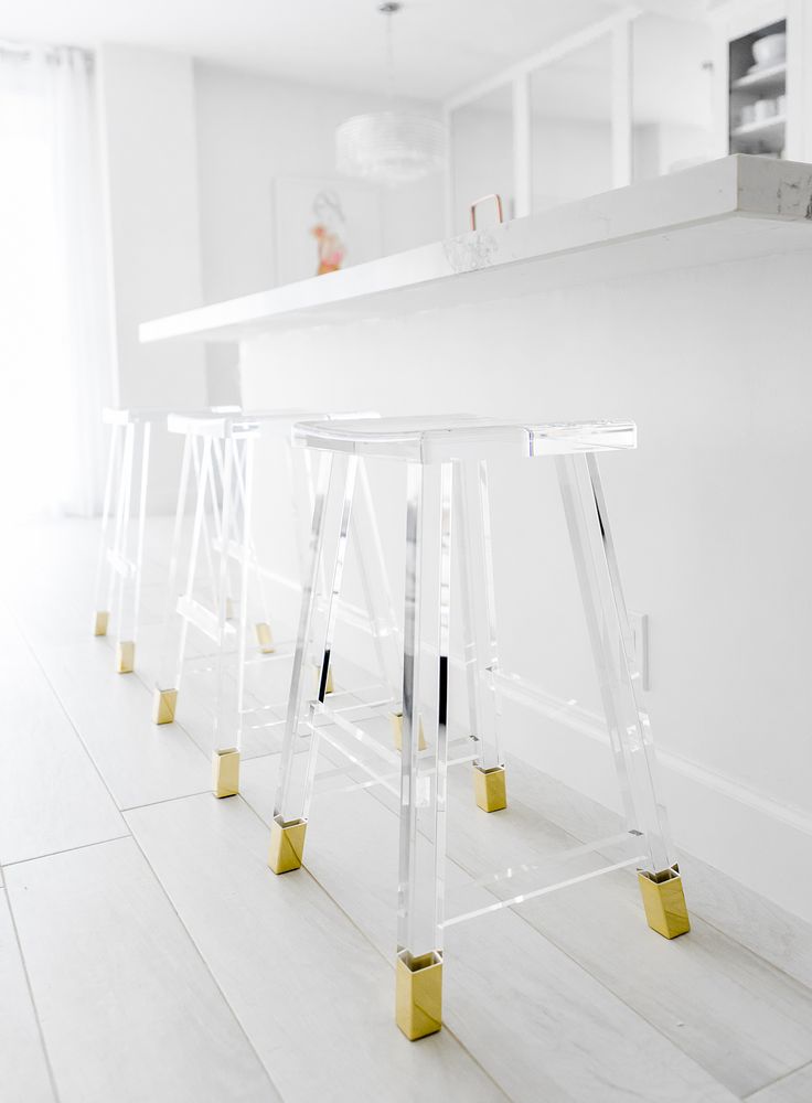 the bar stools are lined up against the wall in the white room with gold legs