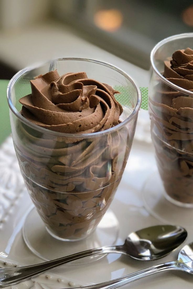 two cups filled with chocolate frosting on top of a table