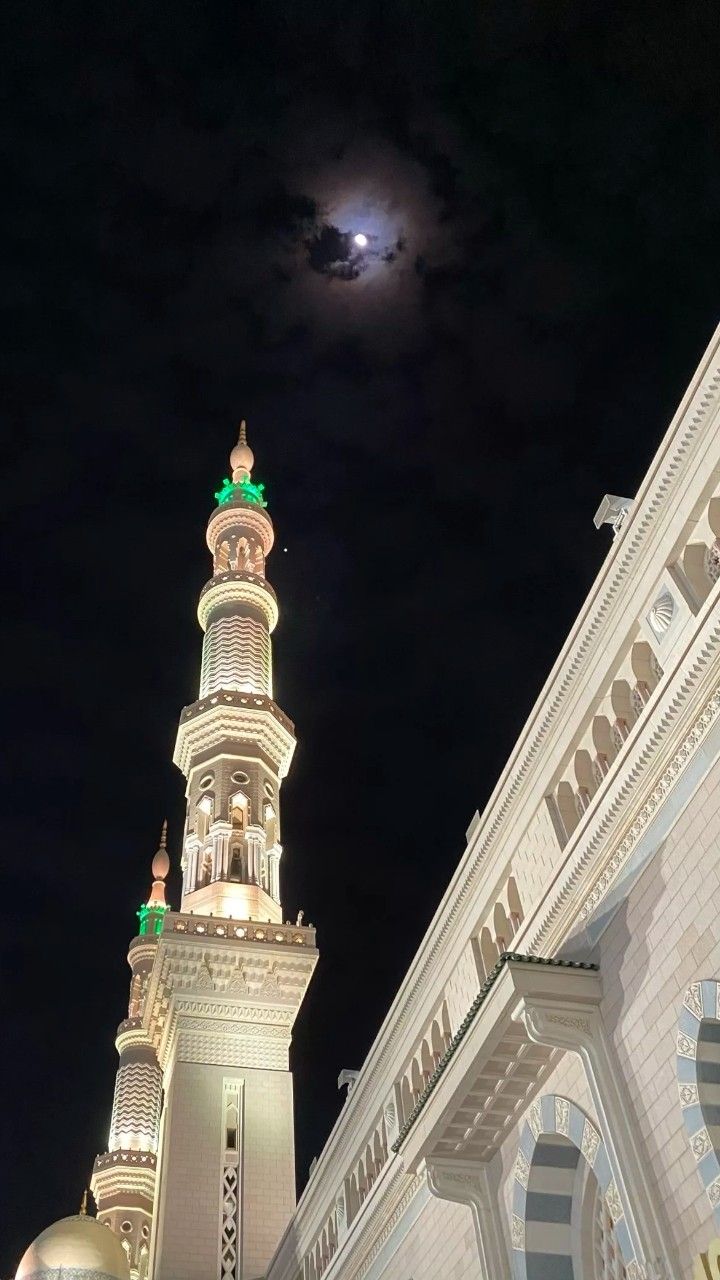 a large white building with a clock on it's side and a full moon in the background