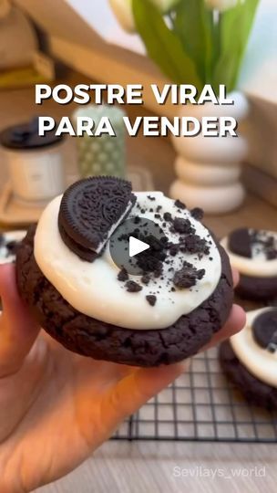 a person holding a chocolate cookie with white frosting and oreo cookies