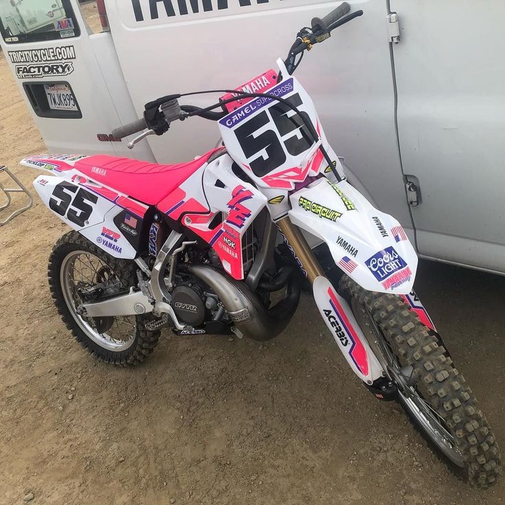 a dirt bike parked in front of a white van with the number 55 on it