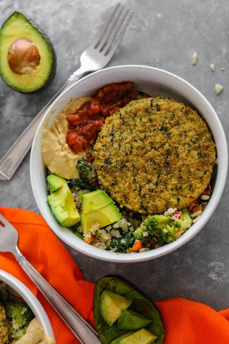 a white bowl filled with food next to an avocado on top of a table