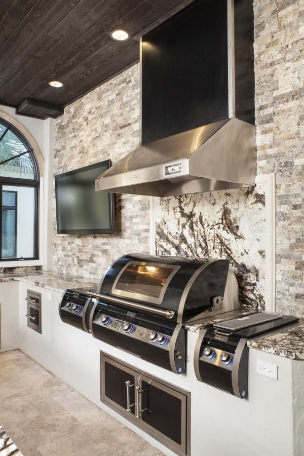 a kitchen with an oven, range and television mounted to the brick wall behind it