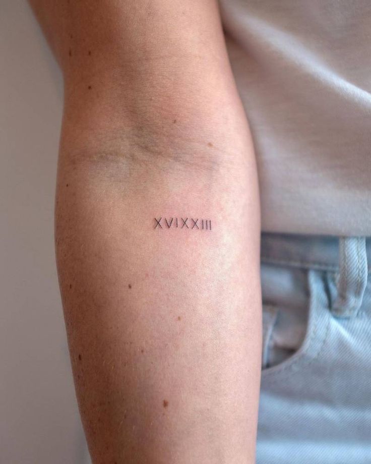 a woman's arm with the word xxvix tattooed on her left arm