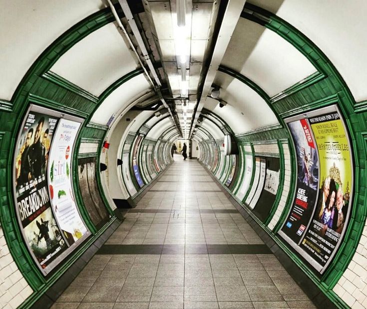 an empty subway station with posters on the walls