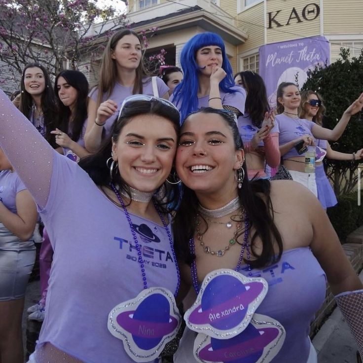 two women in purple shirts are posing for the camera and some people with blue hair