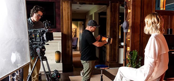 a man and woman standing in front of a camera set up for a photo shoot