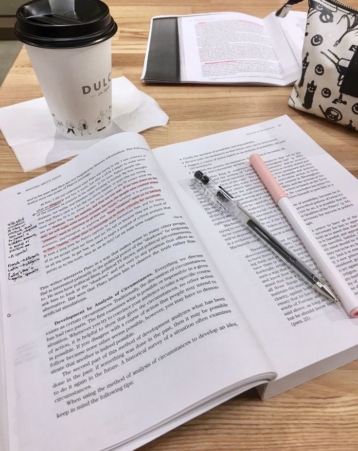 an open book, pen and coffee cup on a table