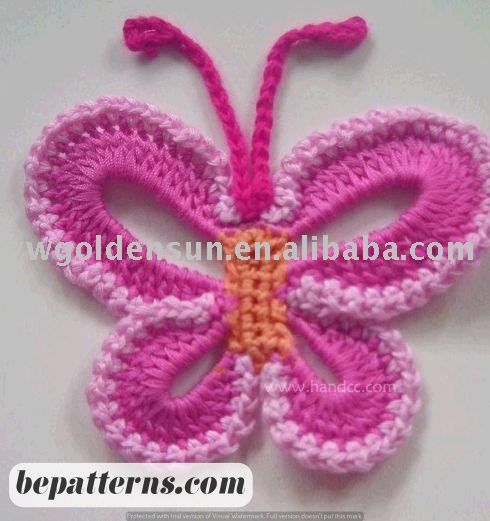 a crocheted pink and orange butterfly on a white surface with words below it