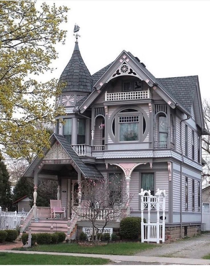 an old victorian style house with pink trim and white pickets on the front porch